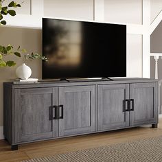 a large flat screen tv mounted on top of a wooden entertainment center in a living room