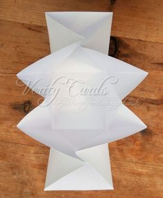 an origami sculpture made out of white paper sitting on top of a wooden table