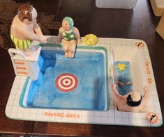 two figurines sitting on top of a table next to a pool and target