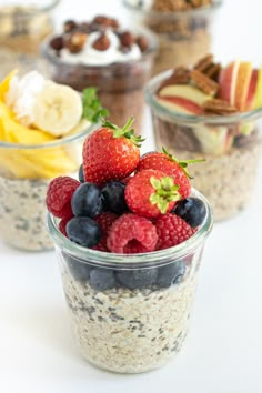 three cups filled with fruit and granola on top of a white table next to bananas