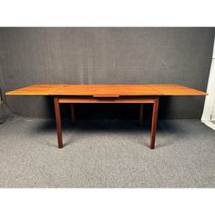 a wooden table sitting on top of a carpeted floor next to a gray wall