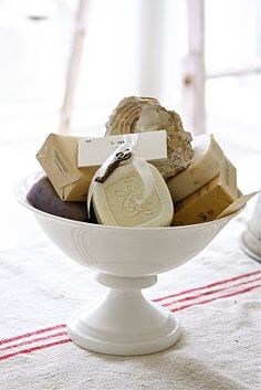 a white bowl filled with different types of soaps on top of a table next to a red and white towel