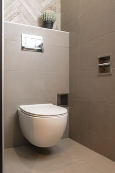 a white toilet sitting inside of a bathroom next to a wall mounted air conditioner