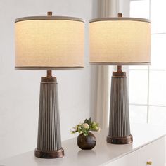 two lamps sitting on top of a table next to a vase with flowers in it