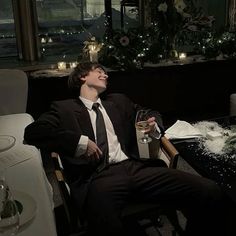 a man in a suit and tie sitting at a table with a glass of wine