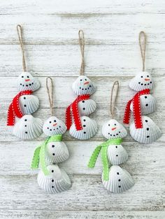 six snowman ornaments hanging from strings on a white wooden surface