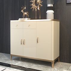 a white cabinet with gold decorations on top and a black wall in the back ground