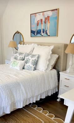 a white bed sitting in a bedroom next to a painting on the side of a wall