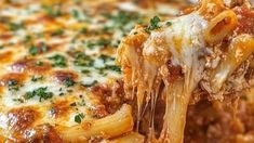 a piece of pasta being lifted from a casserole dish with meat and cheese