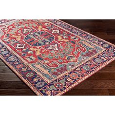 a red and blue area rug with an ornate design on the center, surrounded by wood flooring