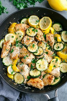 a skillet with chicken, zucchini and lemons