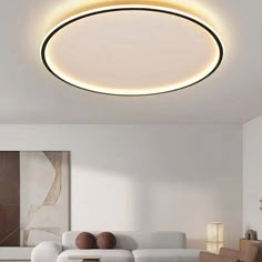 a living room with white furniture and a round light fixture on the ceiling above it