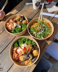 three bowls filled with different types of food on top of a wooden table next to drinks