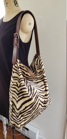 Take this bag with you where ever you go this season. Beautiful shoulder tote / hobo tote bag / bucket tote. FABRIC: Brown beige zebra LINING : Cotton canvas Adjustable Vegan leather shoulder strap that looks like real leather, with metal buckle. Large inside pocket for your cell phone and keys. Open top bag but deep enough to keep your valuables safe. Width: 18 inches Height 16 inches Bottom depth 4 inches Adjustable shoulder strap. Made in Newark, New Jersey by Kirtam Designs Inc. Hand wash an Bucket Tote Bag, Bag Lining, Buckle Bag, Hobo Tote Bag, Zebra Animal, Bucket Tote, Zebras Animal, Handbag Outfit, Brown And Beige