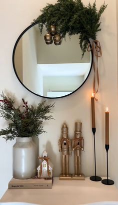 a round mirror on the wall above a shelf with candles and other decorations in front of it