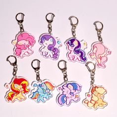 six little pony keychains with different colors and designs on them, all sitting side by side