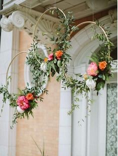 two hoop hanging from the ceiling with flowers and greenery on it's sides