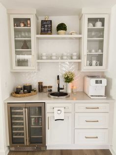 a kitchen with white cabinets and stainless steel appliances in the corner, along with an open shelving unit filled with dishes