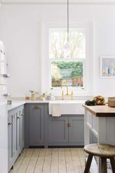 a kitchen with gray cabinets and gold faucet in the window above the sink