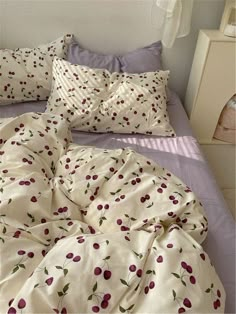 an unmade bed with cherries on it