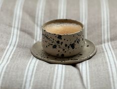 a coffee cup sitting on top of a saucer next to a striped table cloth