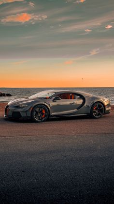 a bugatti car parked on the beach at sunset