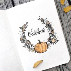 an open notebook with the word october written on it and a pumpkin surrounded by leaves