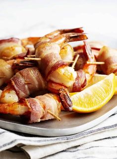 bacon wrapped shrimp on a plate with lemon wedges