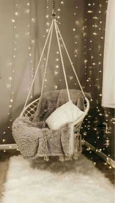 a hanging chair in the corner of a room with lights on the wall behind it