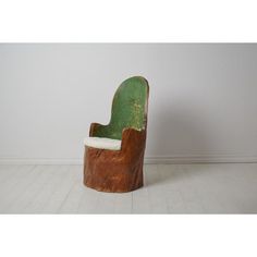 an old wooden chair sitting on top of a white floor next to a wall with a green leather seat