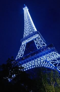 the eiffel tower lit up at night with blue lights on it's sides