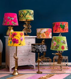 colorful lamps are lined up on a dresser in a room with blue walls and pink carpet