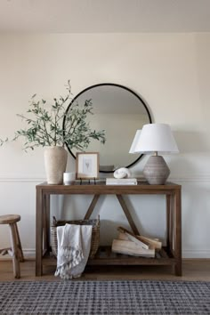 a wooden table topped with a mirror next to a lamp