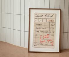 a framed check card sitting on top of a counter next to a wall with white tiles