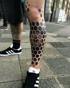 a man's leg with black and white tattoos on it, while he is wearing tennis shoes