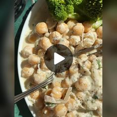 a bowl filled with broccoli and chickpeas covered in sauce next to a fork