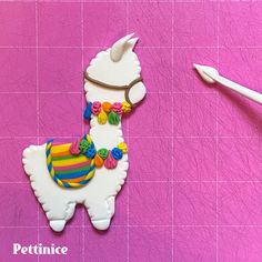 a cookie shaped like an alpaca on a pink background