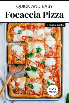 square pizza with cheese and spinach on top in a baking pan next to a wooden spoon