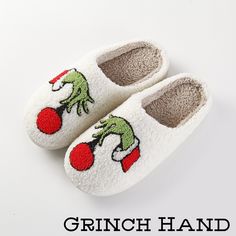 a pair of white slippers with green and red cartoon characters on them, sitting next to the words grinch hand