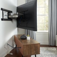 a flat screen tv mounted to the side of a wall next to a wooden table