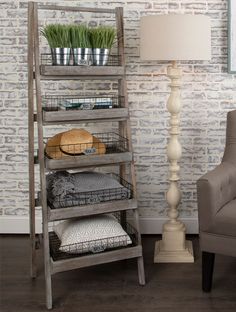 a wooden shelf with baskets on it next to a chair and lamp in front of a brick wall