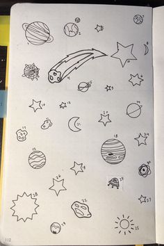 an open notebook with drawings on it and space related items in the pages, including planets