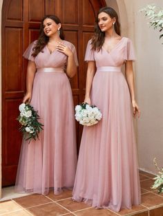 two bridesmaids in pink dresses standing next to each other with flowers on their bouquets