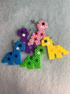 four lego keychains made to look like animals on a gray surface, one has an elephant and the other is a giraffe