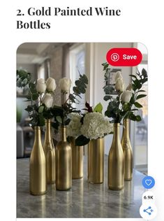 four gold vases with white flowers and greenery in them on a marble countertop