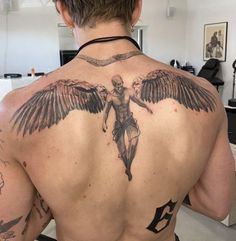 the back of a man with an angel tattoo on his upper and lower back shoulder