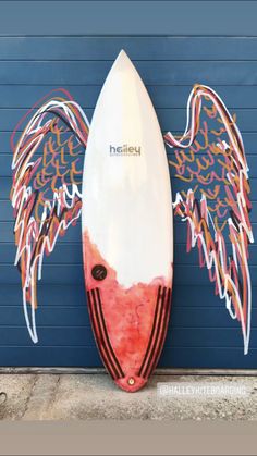 a surfboard with an angel wings painted on it's side next to a garage door