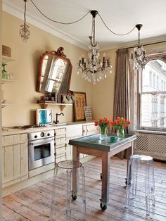 a kitchen with white cabinets and chandelier hanging from the ceiling next to a stove top oven