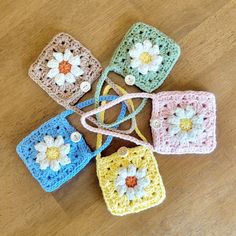 four crocheted square purses with flowers on them sitting on a wooden surface