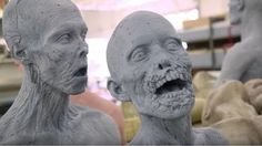 two statues of people with their mouths open in a room full of other sculptures and materials